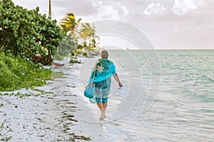 Young woman walking on the beach along the ocean