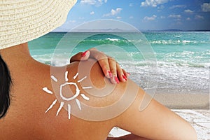 Young woman protecting her skin at the beach, sun shape from sun cream on her back