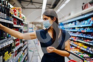 Young woman with protective face mask shopping for groceries in indoor groceries store.Coronavirus COVID-19 concept.Mandatory face