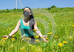 Young woman with protective mask doing yoga exercises in the park