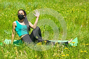 Young woman with protective mask doing yoga exercises in the park