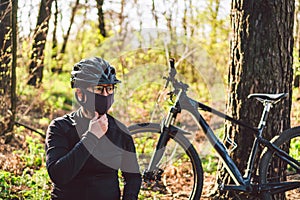 Young woman in protective mask from environmental pollution riding mountain bike on forest road. Cyclist Riding Bike on Trail in