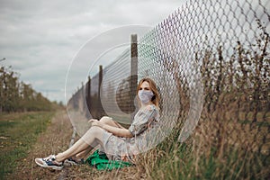 Young woman in protective mask in field. Lady quarantine in the village. Girl and quarantine . Covid-19. Europe