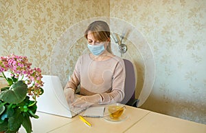 The young woman in the protective mask and gloves works at the computer photo