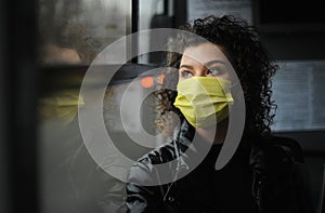 Young woman in a protective mask is riding the bus, observing the quarantine measures.