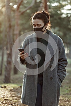 Young woman in protective mask with smartphone.