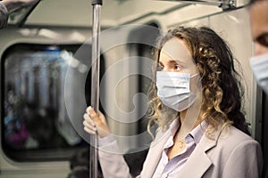 young woman in a protective mask standing in the subway car.