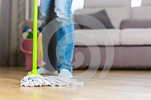 Woman in protective gloves using a wet-mop while cleaning floor