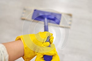 Girl in protective gloves cleaning floor using flat wet mop