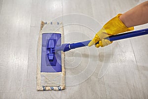 Girl in protective gloves cleaning floor using flat wet mop