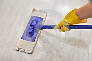 Girl in protective gloves cleaning floor using flat wet mop