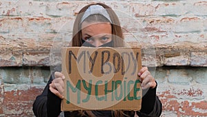 Young woman protester holds MY BODY MY CHOICE sign. Girl protesting against anti-abortion laws. Feminism power concept