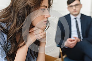 A young woman at a psychiatrist& x27;s or psychologist& x27;s appointment is worried, holds her hands to her face and