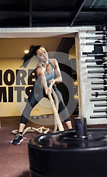 Young woman pulling rope attached to weights