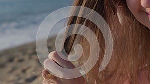 Young woman pulls strand of hair combing through with comb