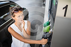 Young woman pumping gas at gas pump