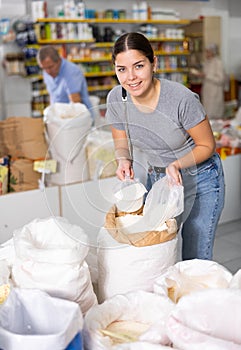 Young woman purchaser buying white flour in supermarket