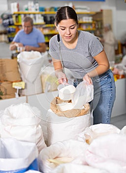Young woman purchaser buying white flour in supermarket