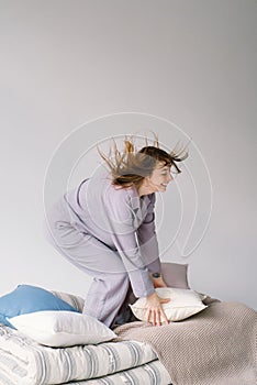 Young Woman in Purple cozy pajamas in a Play with Pillow Indoors