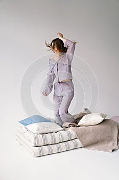 Young Woman in Purple cozy pajamas in a Play with Pillow Indoors