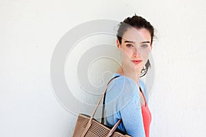 Young woman with purse against white wall