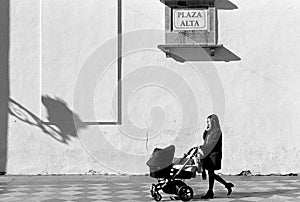 Young Woman Pushing Baby Buggy While Talking on Mobile Phone.