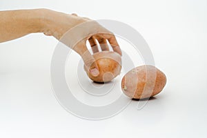 A young woman put a potato on the table. Two fresh potatoes isolated on white background with selective focus