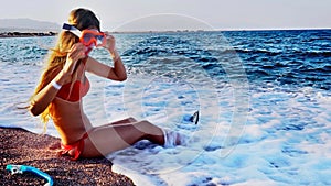 Young woman put on snokeling goggles and diving fins