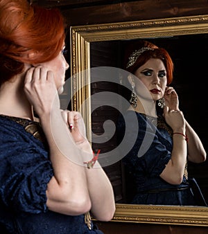 Young woman puts on beautiful earrings in front of mirror. beautiful girl in vintage style.