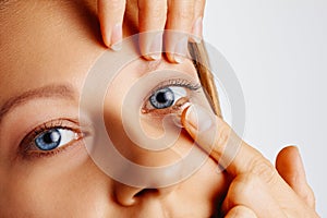 Young woman puts contact lens in her eye. Eyewear, eyesight and vision, eye care and health, ophthalmology and optometry concept