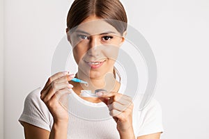 A young woman puts on contact lenses in her apartment