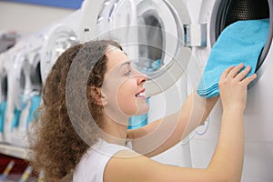 Young woman puts linen in washing machine in shop photo