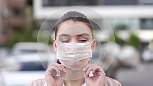 Young woman puts on medical mask to face going out to street