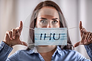 A young woman puts on a protective mask with the inscription IHU