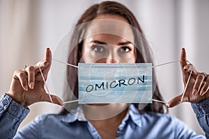 A young woman puts on a protective mask with the inscription Omicron photo