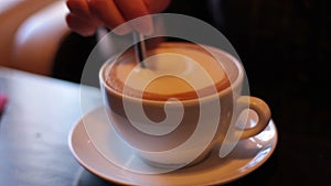 Young woman puts sugar in coffee and stir with a spoon.