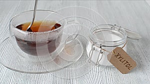 Young woman puts sugar substitute xylitol in a cup of tea, closeup