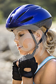 Young woman putting on bicycle helmet.
