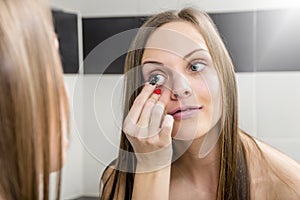 Young woman putting contact lens