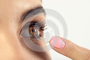 Young woman putting contact lens in her eye