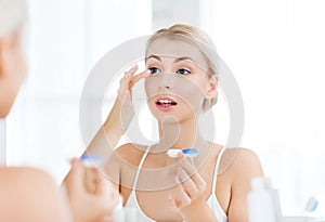 Young woman putting on contact lenses at bathroom