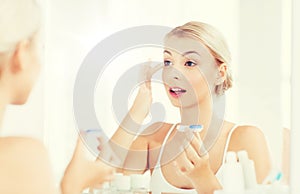 Young woman putting on contact lenses at bathroom