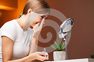 A young woman is putting on contact lenses in front of the mirror.