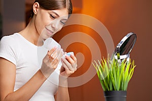 A young woman is putting on contact lenses in front of the mirror.