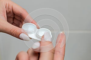 Young woman putting on contact lenses for vision correction