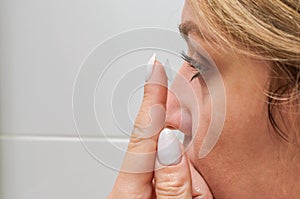 Young woman putting on contact lenses for vision correction