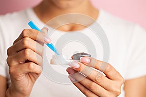 Young woman putting eye contact lens on her eyes