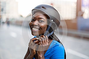 Young woman putting her cycling helmet on