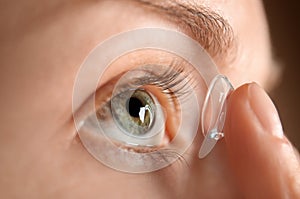 Young woman putting lens in her eye, closeup