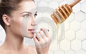 Young woman putting lipbalm with honey on lips.